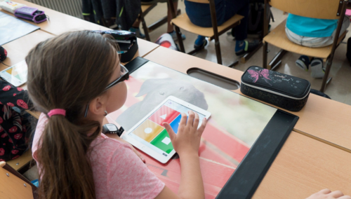 Ein Schulkind an ihrem Schreibtisch hat ein Smart Pad vor sich.