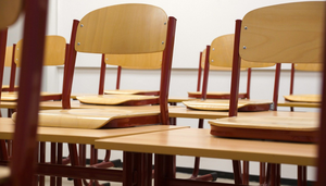 Hochgestellte Stühle auf Tischen in einem leeren Klassenzimmer.